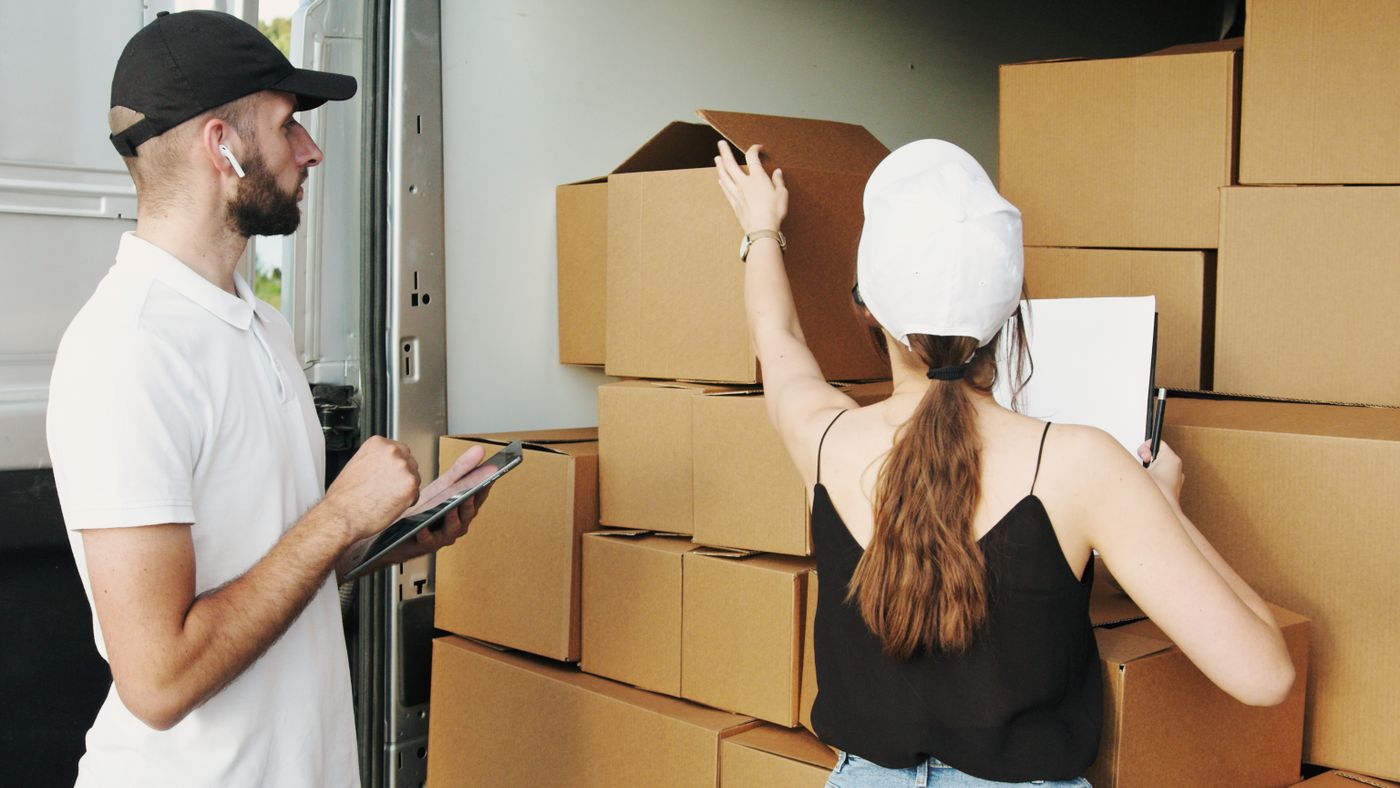 Movers organizing stacked cardboard boxes inside a cargo van
