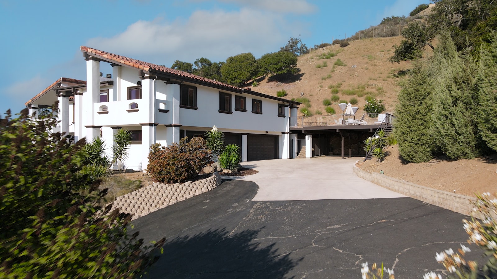 Residential house with a hillside driveway and dirt embankment that needs grading and drainage shaping