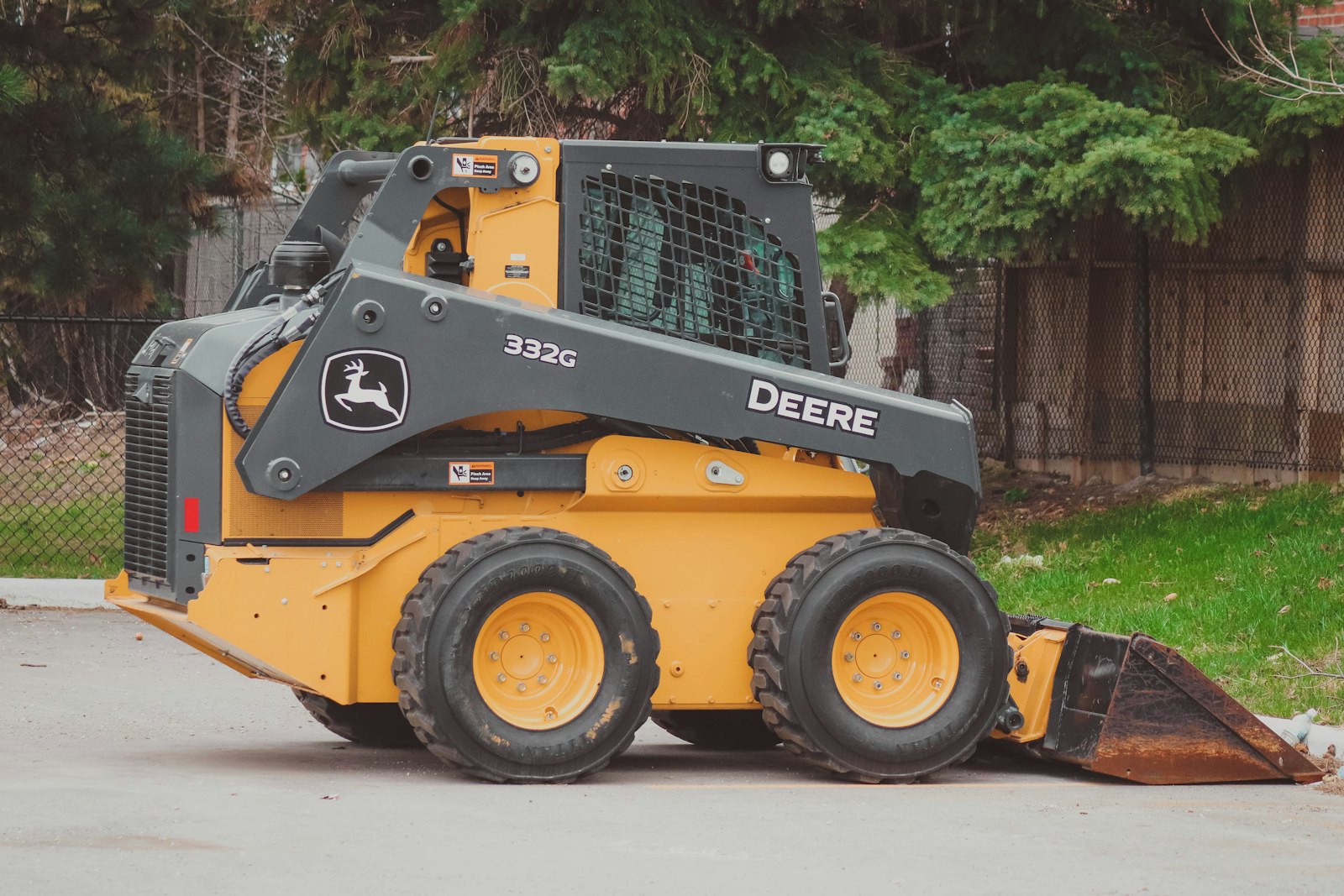Yellow skid steer loader with bucket attachment ready for residential yard work